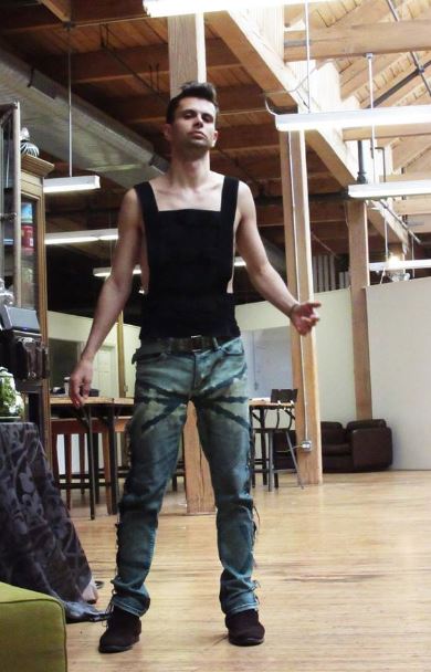 Cómodo Cal Garcia en sus favoritos Verdes Eco-Couture Jeans en el Diseñador de Estudio Loft. Aquí también vemos la alta costura camiseta sin mangas de forma ajustada con bloques semi-transparentes.